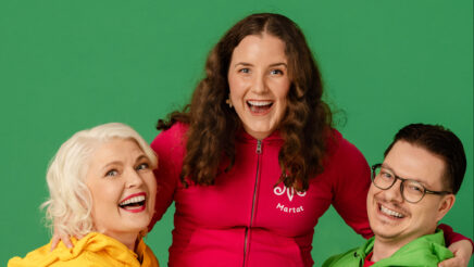 Kuvassa kaksi naista ja yksi mies katsovat iloisesti kameraan. Kuvan reunalla seisovat mies ja nainen kannattelevat käsillään heidän sylissään keskellä istuvaa naista. Kaikilla on päällään värikkäät martta-hupparit.